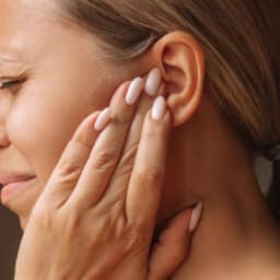 Woman holds ear in pain