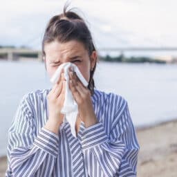 Woman on the beach blowing her nose