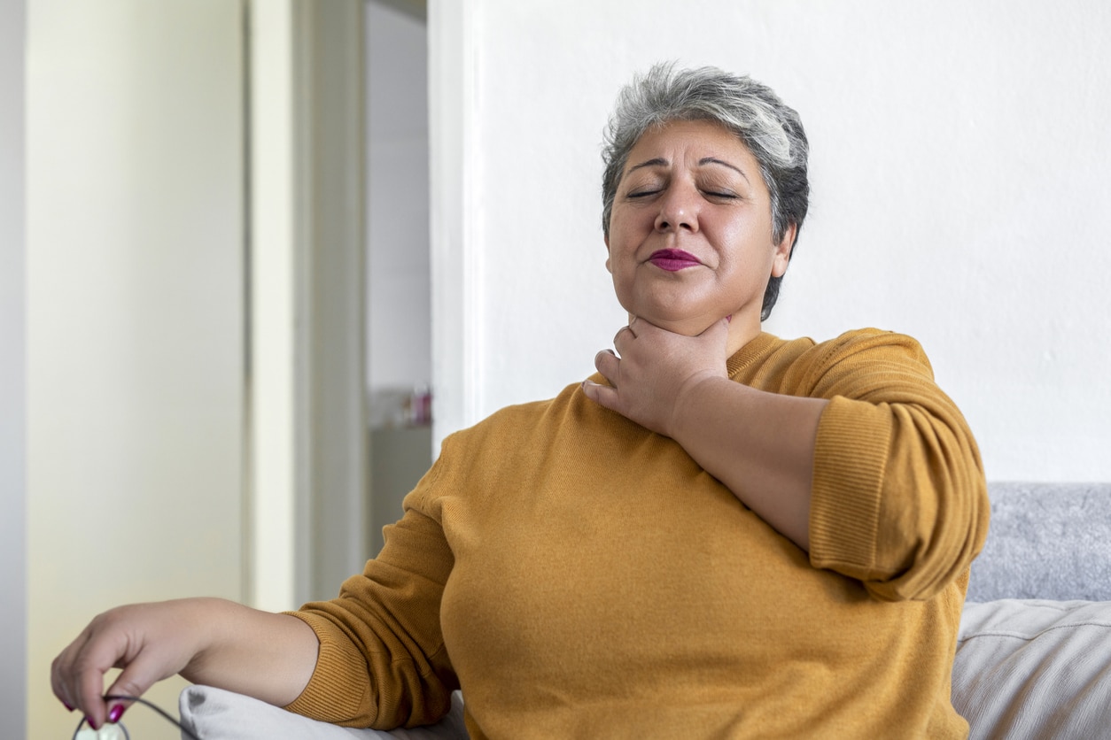 Woman holding her throat.