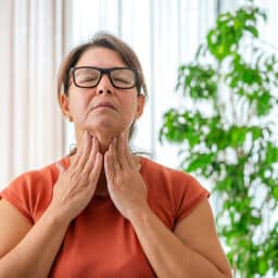 Woman holding her throat, looking uncomfortable