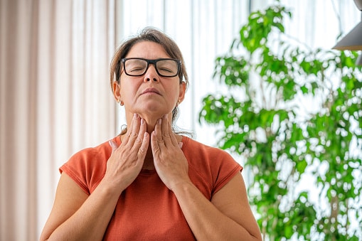 Woman holding her throat, looking uncomfortable.