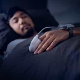 Man in bed at home with sleep monitors on his finger and sleep.