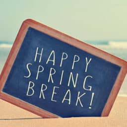 Happy spring break written in a blackboard on the sand of a beach, with a filter effect