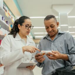 A pharmacist explaining a medication to a customer in the pharmacy.